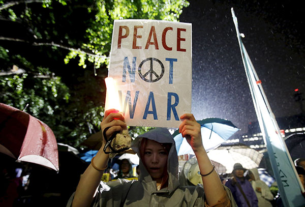 A protester holding a placard takes part in a rally against Japan's Prime Minister Shinzo Abe's security bill and his administration in front of the parliament in Tokyo, Japan, September 17, 2015. A panel in Japan's upper house on Thursday approved legislation for a security policy shift that would allow troops to fight abroad for the first time since World War Two, a ruling party lawmaker said. REUTERS/Yuya Shino